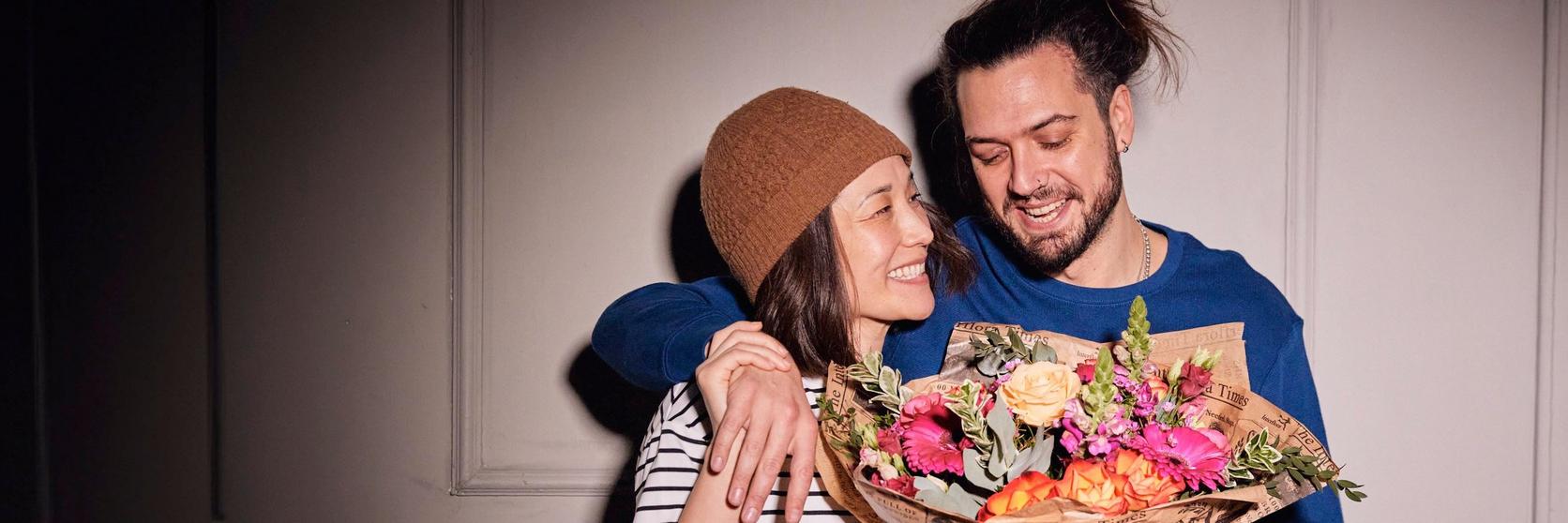 man-and-woman-smiling-with-bright-bouquet-flowers